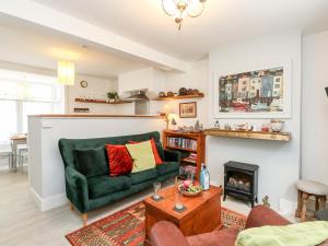 ein Wohnzimmer mit einer grünen Couch und einem Kamin in der Unterkunft Harbour Catch Cottage in Weymouth