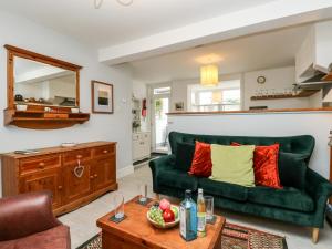 ein Wohnzimmer mit einer grünen Couch und einem Tisch in der Unterkunft Harbour Catch Cottage in Weymouth