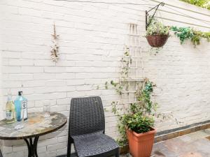 einen Tisch und einen Stuhl neben einer weißen Ziegelwand in der Unterkunft Harbour Catch Cottage in Weymouth