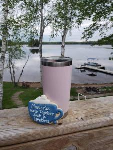 a cup of coffee sitting on a table next to a lake at Birch Bark Lodge Condo in Hayward