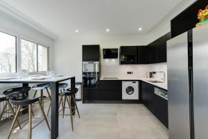 a kitchen with black cabinets and a table with stools at Swan Lake - Design apartment facing Lake Annecy in Annecy