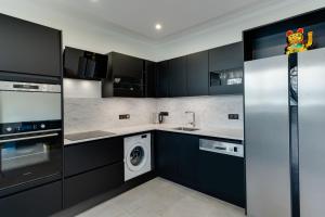 a kitchen with black cabinets and a washer and dryer at Swan Lake - Design apartment facing Lake Annecy in Annecy