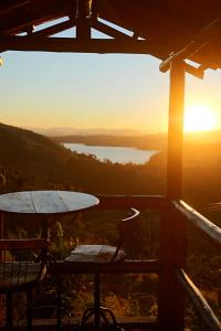 a table and chairs on a balcony with a view of a lake at Pousada do Xerife in Caconde