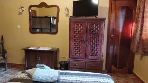 1 dormitorio con TV y un gran armario de madera en Posada Los Chaneques Catemaco en Catemaco