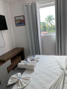 1 dormitorio con 2 toallas en una cama con ventana en Flat Manamar, en Porto de Galinhas
