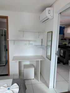 a white kitchen with a table and a mirror at Flat Manamar in Porto De Galinhas