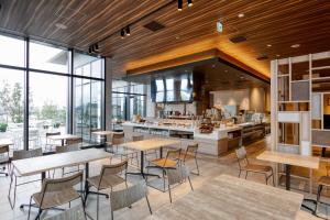 a restaurant with tables and chairs and a kitchen at Glocal Hotel Itoshima in Itoshima