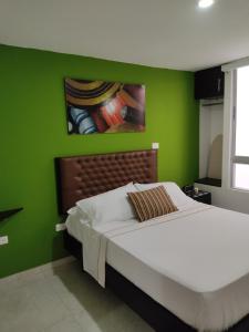a bedroom with a green wall with a bed at Escala Hotel in Valledupar