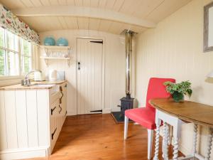 a kitchen with a table and a red chair at Orchard in Wadebridge