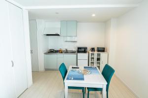 宮古島的住宿－Ecot Kugai 1，小厨房配有白色的桌子和椅子