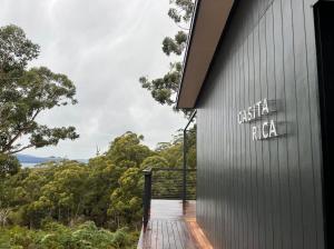 a wooden walkway leading to a building with a sign on it at Casita Rica in Glendevie