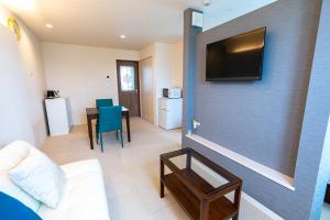 a living room with a couch and a tv on a wall at Ecot Sunayama Beach in Miyako Island