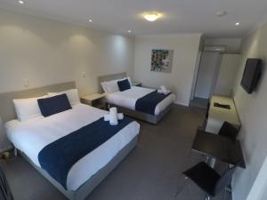 a hotel room with two beds and a television at Lincoln Cottage Motor Inn in Wagga Wagga