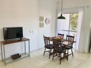 a dining room with a table with chairs and a television at Novo Porto- Apartamentos 2 quartos, varanda, cozinha integrada in Piracicaba