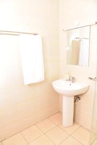 a white bathroom with a sink and a mirror at Karen View Palace Apartments in Nairobi