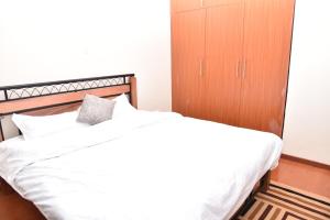 a bedroom with a white bed with a wooden cabinet at Karen View Palace Apartments in Nairobi