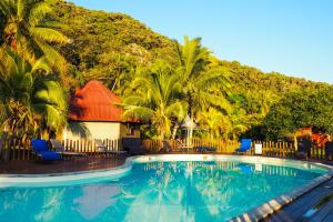 a swimming pool in front of a resort with palm trees at Hotel Oasis de Kiamu in Lifou