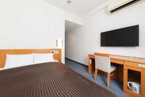 a hotel room with a bed and a desk and a tv at The OneFive Osaka Sakaisuji in Osaka