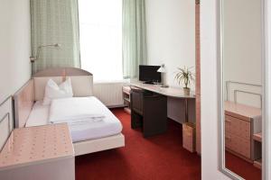 a bedroom with a bed and a desk with a computer at Hotel Adler in Greifswald