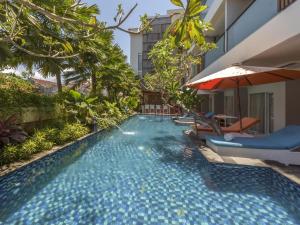 una piscina infinita en un hotel con sillas y sombrilla en Destiny Boutique Hotel, en Seminyak