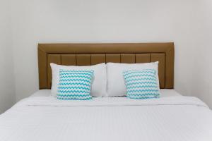 un letto con cuscini bianchi e blu di Social Hub by TwoSpaces a Giacarta