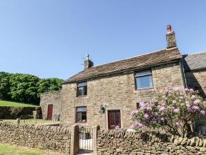 an old stone house with a stone wall at Keepers Cottage in Chapel en le Frith