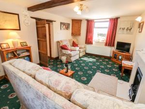 ein Wohnzimmer mit einem Sofa und einem TV in der Unterkunft Keepers Cottage in Chapel en le Frith