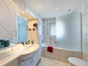 uma casa de banho com um lavatório, uma banheira e um espelho. em Bergwild em Garmisch-Partenkirchen