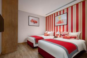 two beds in a hotel room with red and white stripes at Mangrove Tree Resort World Sanya Bay -Elader Palm Tower in Sanya