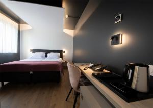 a bedroom with a bed and a desk with a phone at Hôtel Restaurant & Spa du Tremplin in Bussang