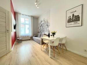 - un salon avec une table, des chaises et un canapé dans l'établissement Apartamenty Stary Toruń, à Toruń