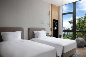 two beds with white sheets in a room with a window at EVEN Hotel Shenzhen Nanshan by IHG in Shenzhen