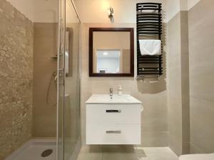 La salle de bains est pourvue d'un lavabo blanc et d'une douche. dans l'établissement Apartamenty Stary Toruń, à Toruń