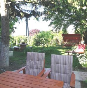 twee stoelen en een houten tafel in de tuin bij Árnyas Vendégház in Hajdúszoboszló