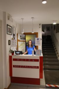 une femme debout au comptoir d'un magasin dans l'établissement Hotel Mezzaluna, à Trévise