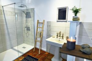 a bathroom with a sink and a shower with a candle at Le Bruit de l'eau (Chambre Boudoir) in Labeaume