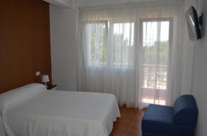 1 dormitorio con 1 cama, 1 silla y 1 ventana en Hostal Solymar, en Louro