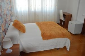 a bedroom with a white bed with a orange blanket at Hostal Solymar in Louro