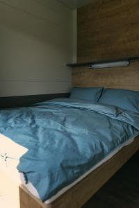 1 cama grande con sábanas azules y cabecero de madera en Natura Fina Resort, en Ravne na Koroškem