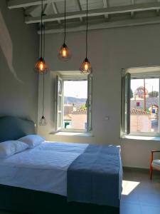 a bedroom with a bed and two windows at Metochi Athentic Hospitality in Hydra
