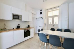 - une cuisine avec des placards blancs, une table et des chaises dans l'établissement Premium Apartment by Hi5 - ASTORIA 4 bedroom, à Budapest