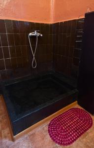 a bath tub with a shower and a red rug at Karosta Prison in Liepāja