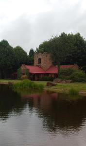 a building with a red roof next to a body of water at Critchley Hackle Dullstroom Towers in Dullstroom