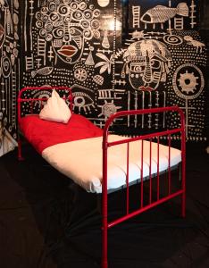 a red bed in a room with a black and white wall at Karosta Prison in Liepāja