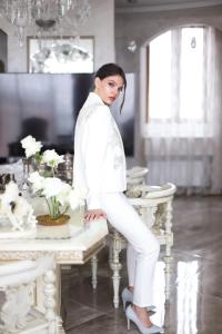 Uma mulher vestida de branco sentada numa mesa. em Hotel "Mandarin Clubhouse" em Kharkov