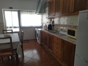 a kitchen with a sink and a table and a microwave at Casa S Nicolau 1 Near the beach in Lourinhã