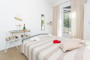 ein weißes Schlafzimmer mit einem Bett mit einer roten Blume darauf in der Unterkunft Studios IM in Dubrovnik