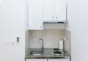 una cocina con armarios blancos y fregadero en Studios IM, en Dubrovnik