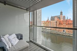 een kamer met een balkon met uitzicht op een rivier bij Granaria RR DeLuxe Apartment Old Town in Gdańsk