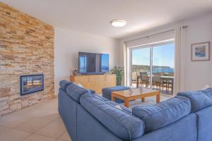 a living room with a blue couch and a fireplace at Simply Salema - Casa das Estevas in Budens